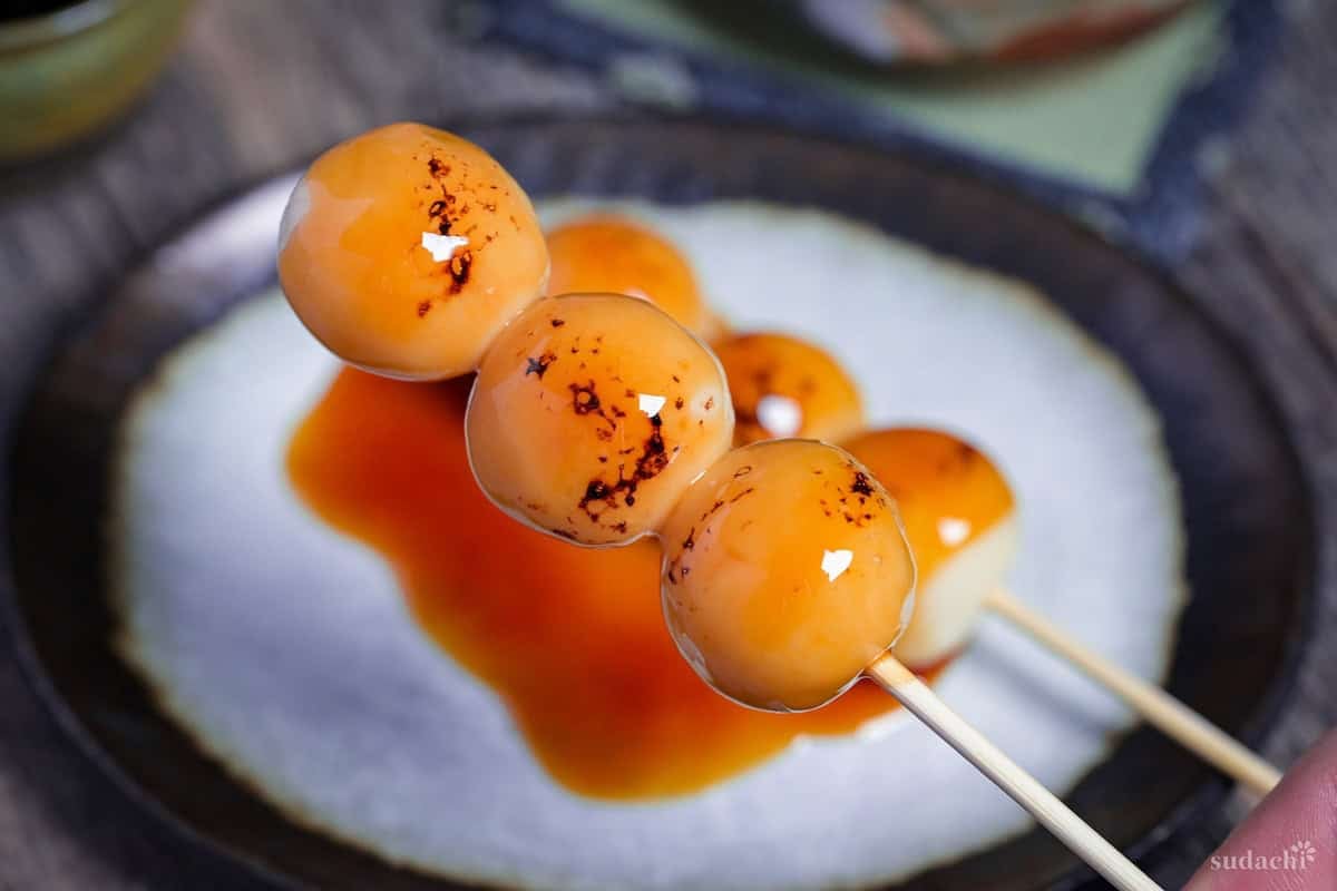 Holding up one homemade tofu mitarashi dango