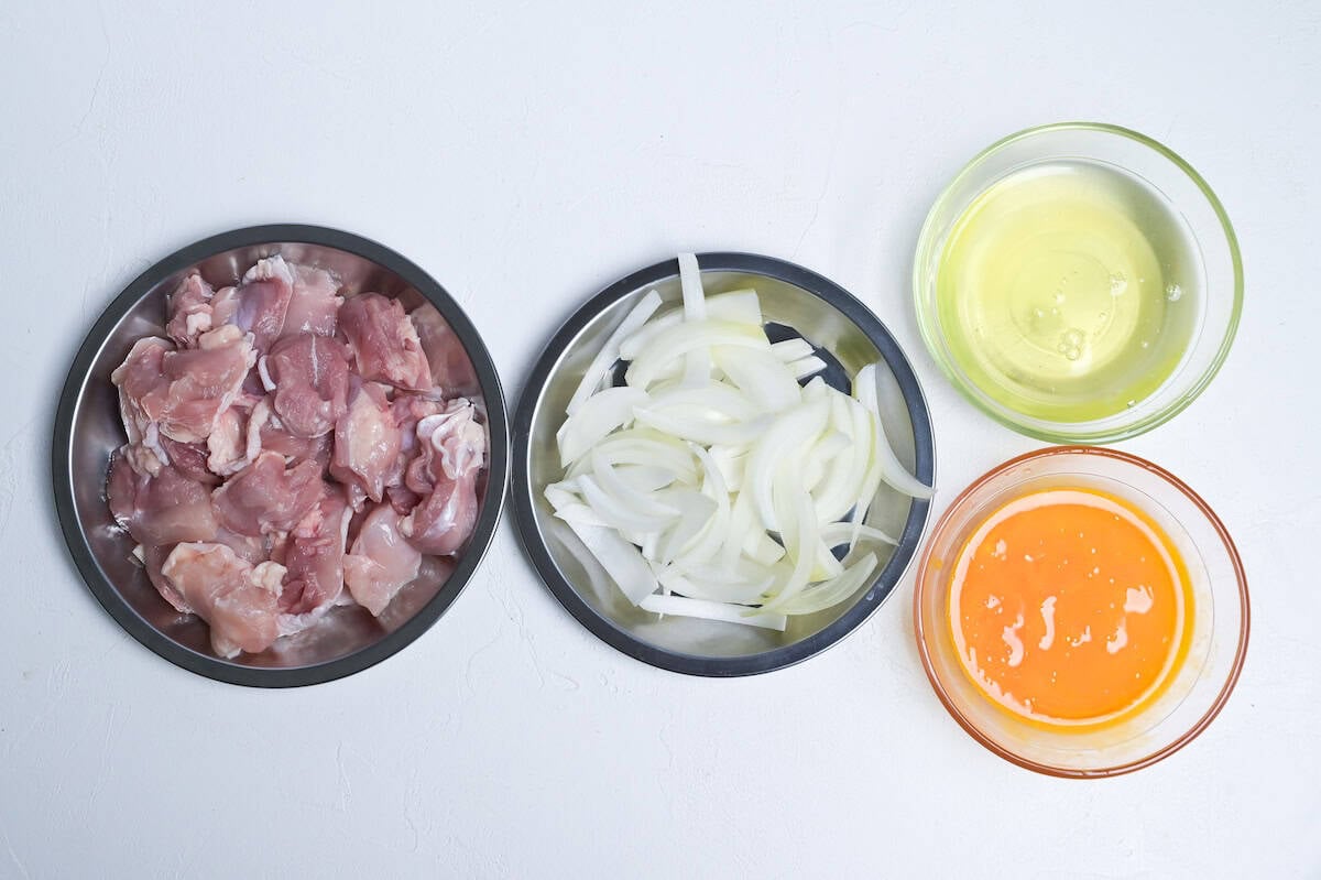 roughly cut chicken thigh, sliced onions and separated eggs all on separate prep plates/dishes to prepare for making oyakodon