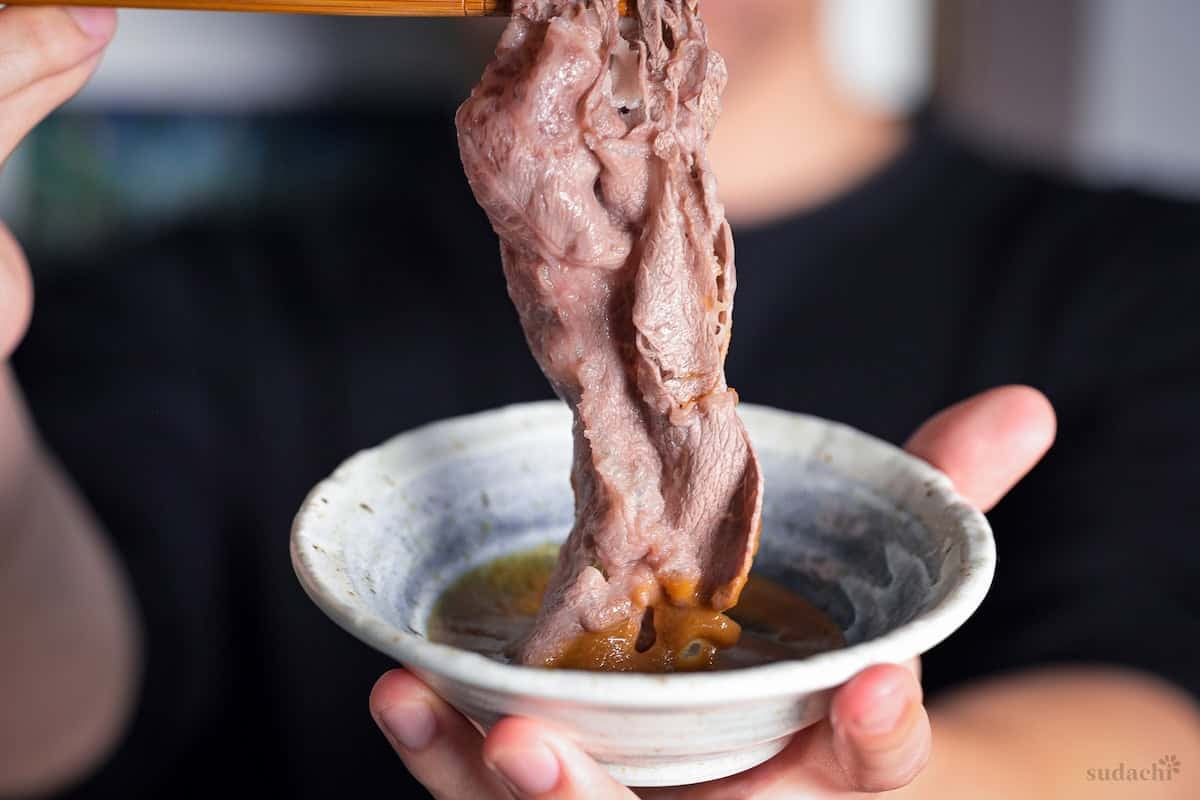 Yuto Omura dipping shabu shabu wagyu beef in homemade sesame dipping sauce
