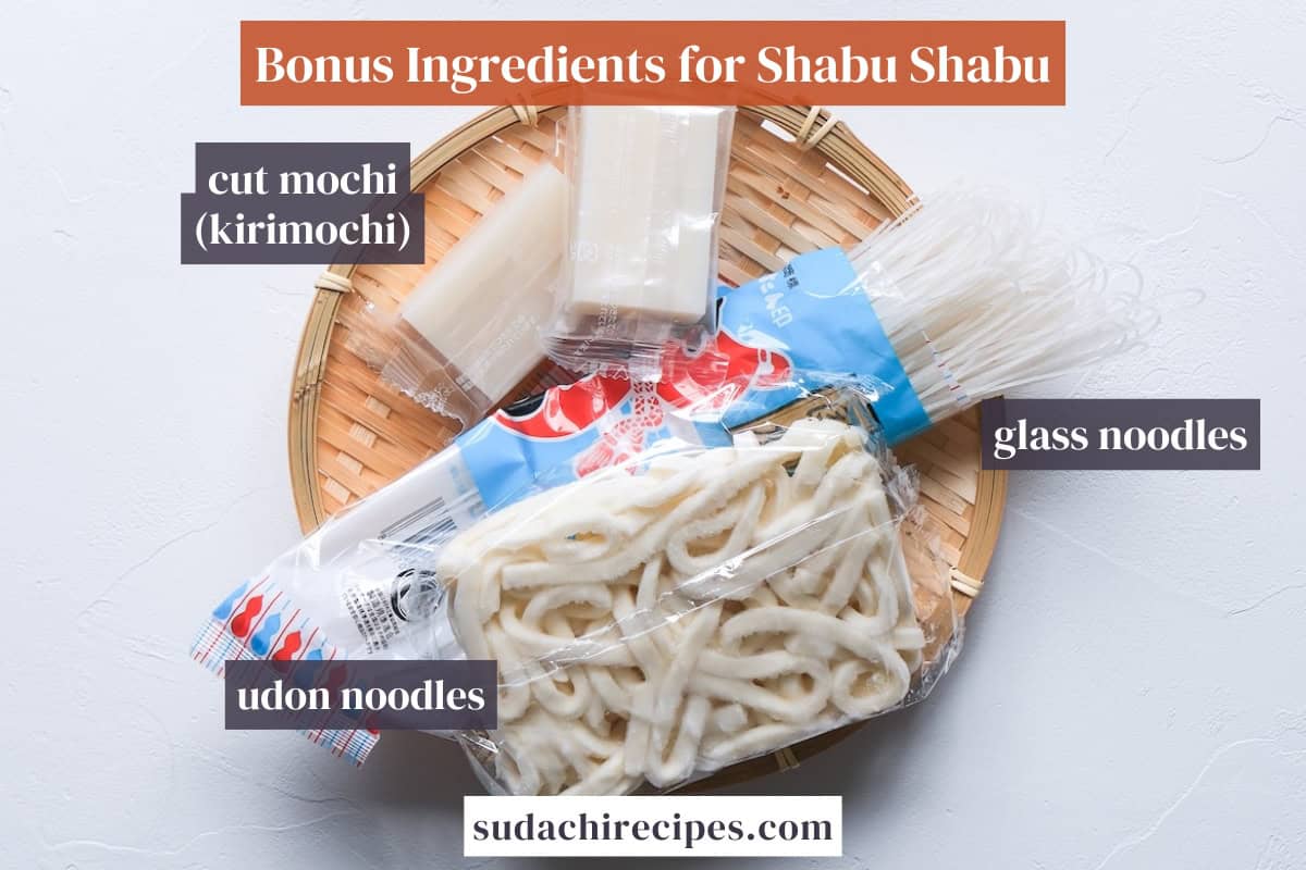 Cut mochi, glass noodles and udon noodles in packaging on a bamboo tray (bonus shabu shabu ingredients)