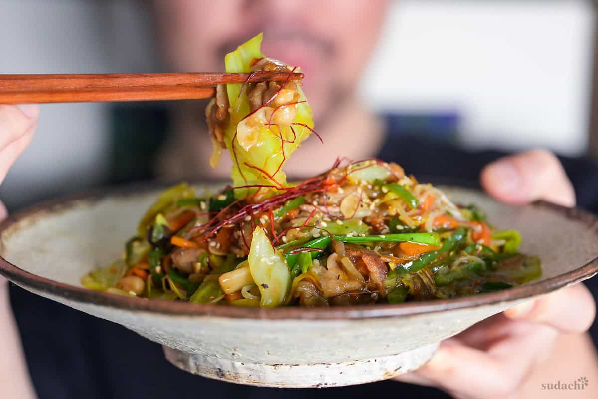 Yuto Omura holding up a plate of niku yasai itame (Japanese meat and vegetable stir fry)