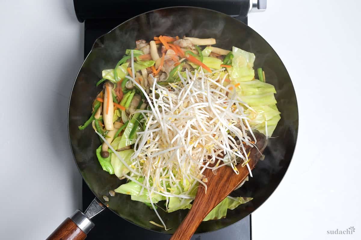 beansprouts added to niku yasai itame in a wok on the stove top.