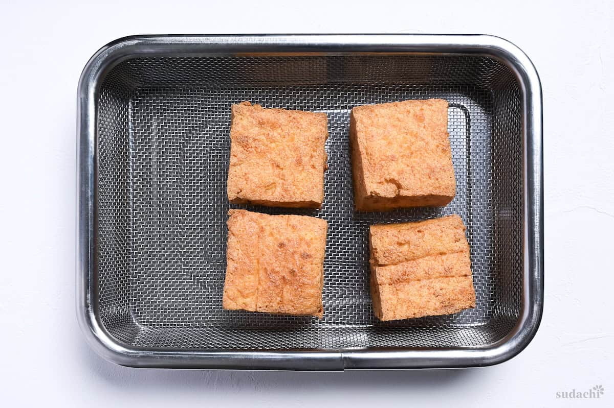 4 pieces of atsuage tofu on a wire rack over a metal container