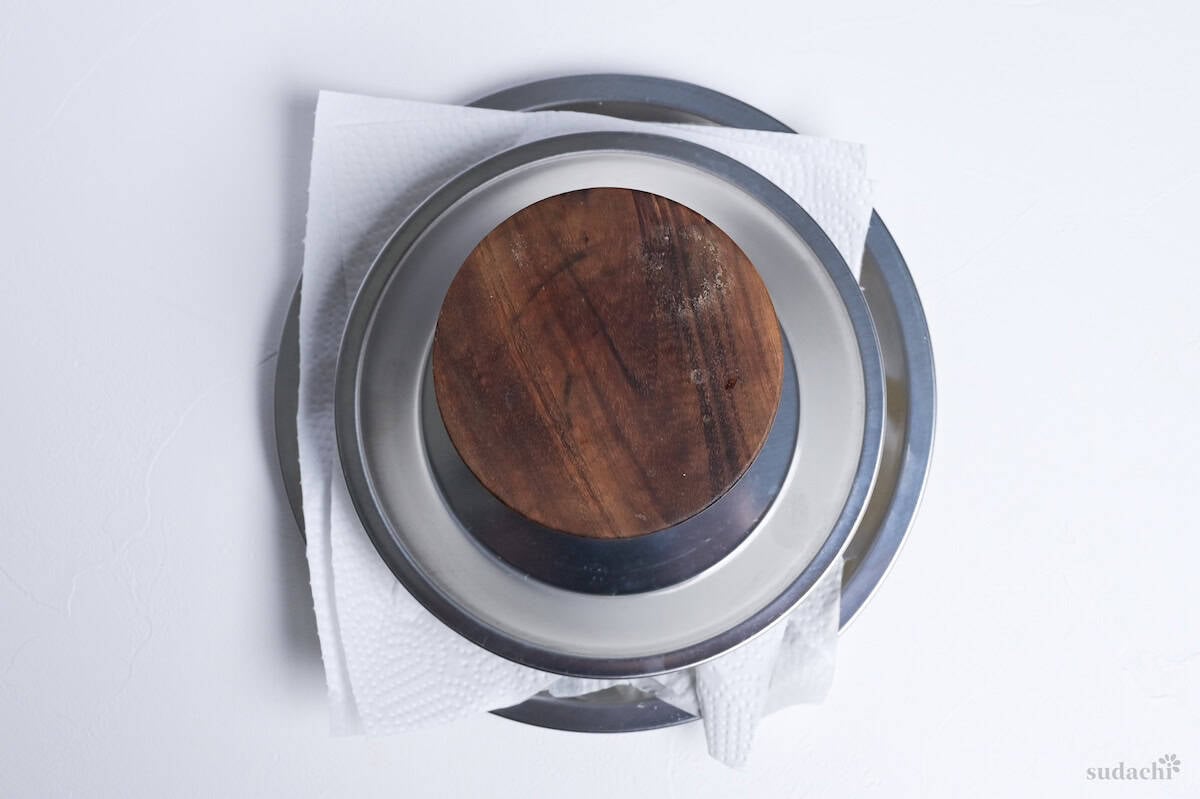 a plate and a weight on top of firm tofu to press it