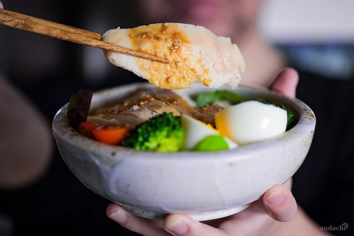 Yuto Omura holding up Japanese chicken salad with wafu dressing in a mottled bowl