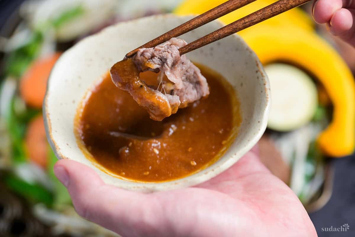Dipping cooked lamb in homemade jingisukan sauce