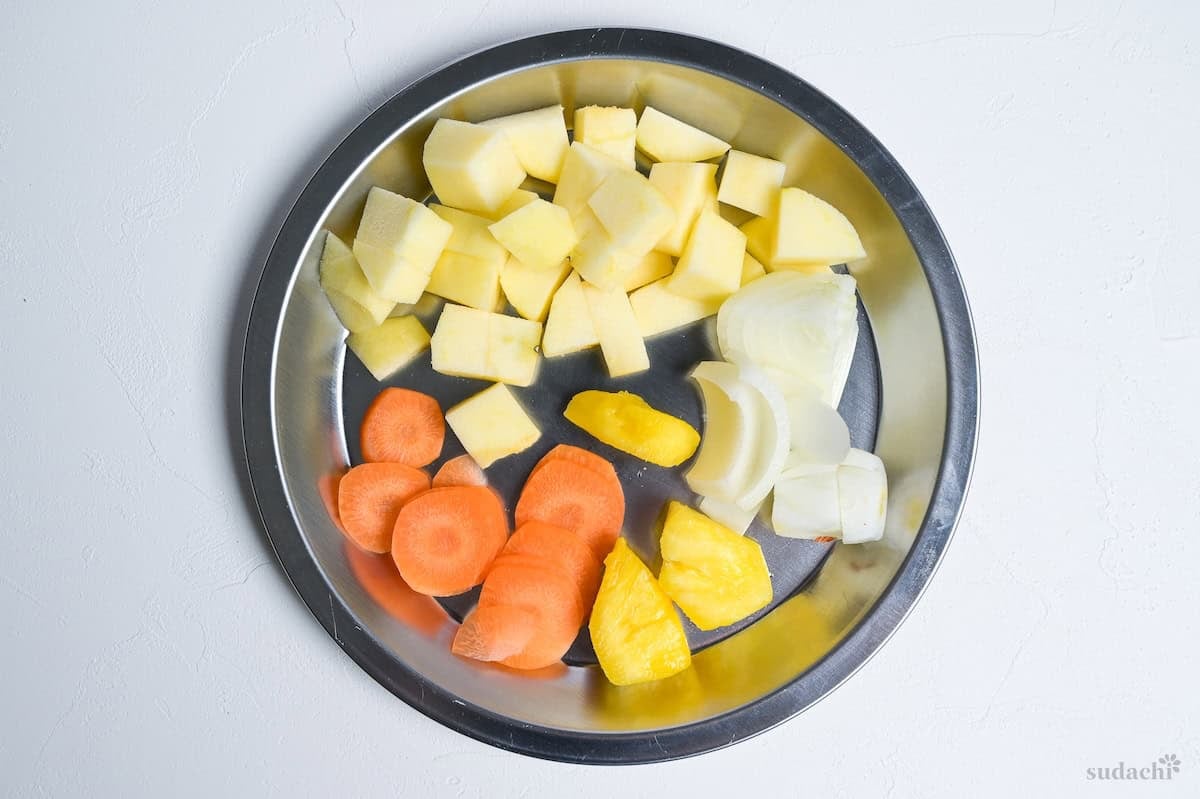 cut apple, carrot, pineapple and onion on a silver plate
