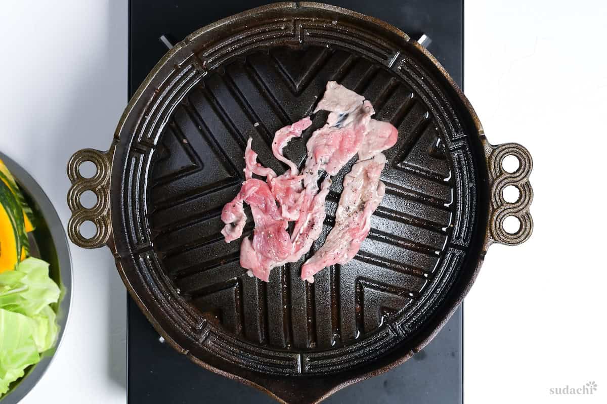 Thinly sliced lamb seasoned with salt and pepper on a Mongolian style BBQ grill to make Hokkaido style Jingisukan