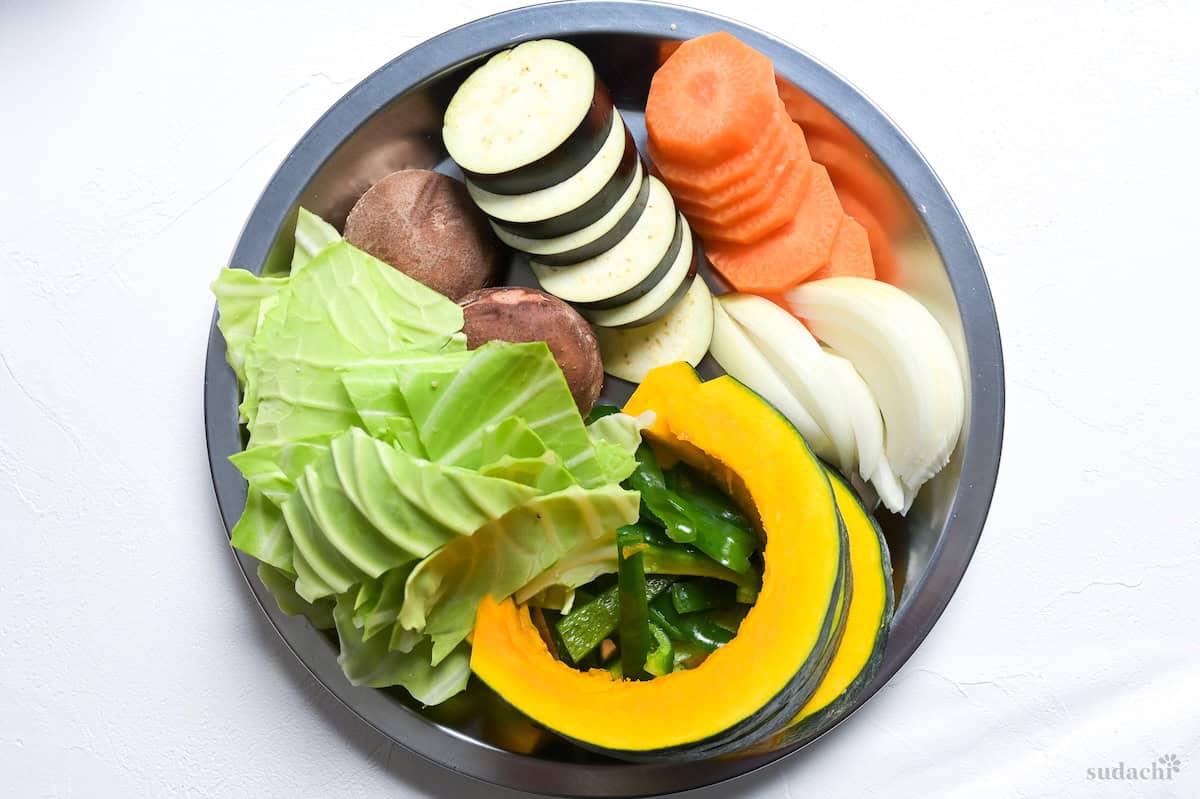 Cut cabbage, shiitake mushrooms, eggplant, carrot, onions, bell peppers and kabocha squash for jingisukan on a silver plate