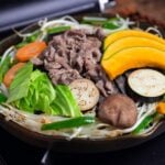 Hokkaido style Jingisukan with thinly sliced lamb and vegetables on a Mongolian style BBQ grill