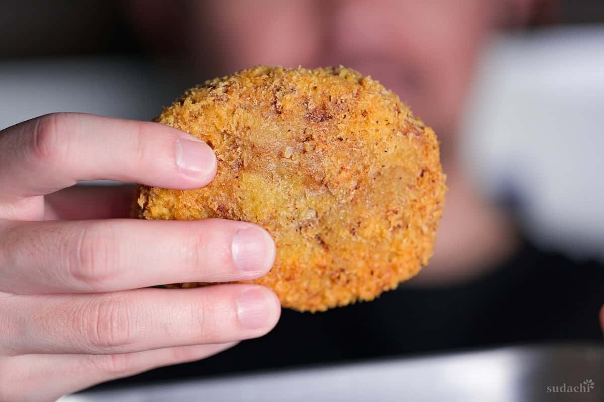 Yuto Omura holding up a Japanese meat and potato korokke