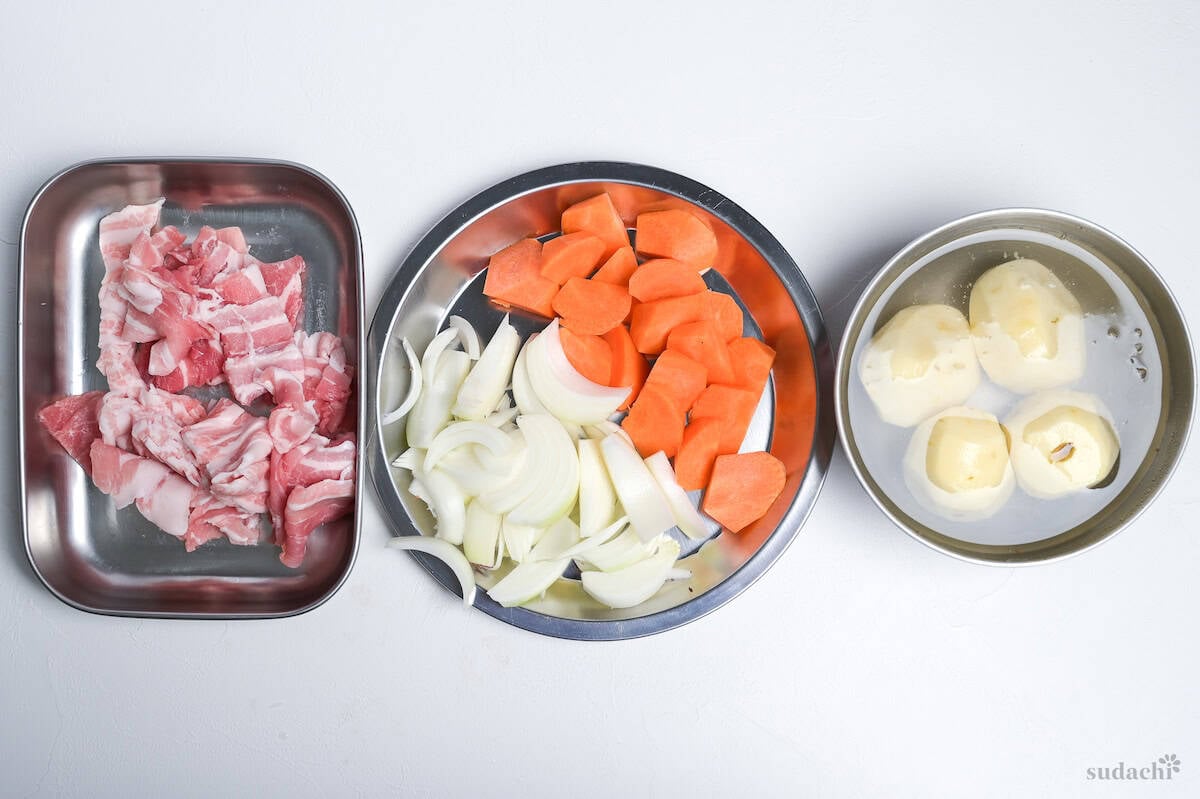 Mise en place for nikujaga: cut pork, sliced onions, cut carrots, peeled potatoes in water.