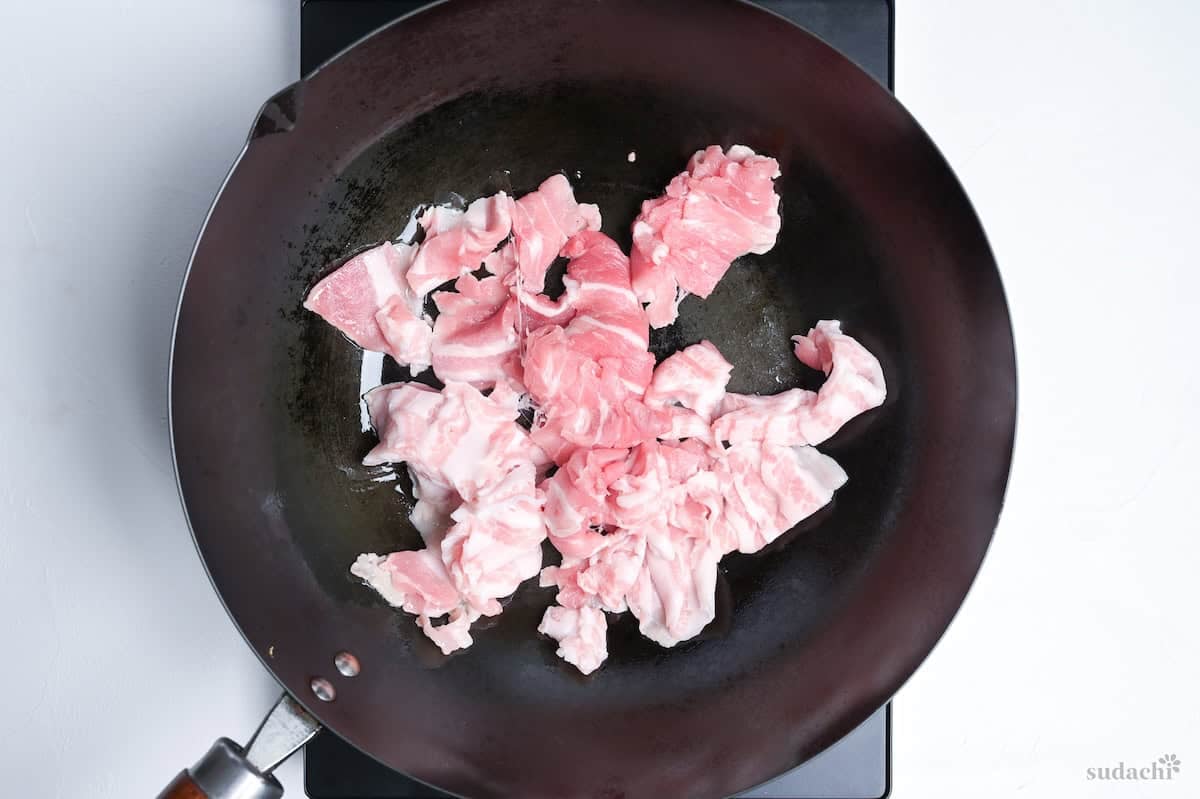 frying thinly sliced pork in a large wok