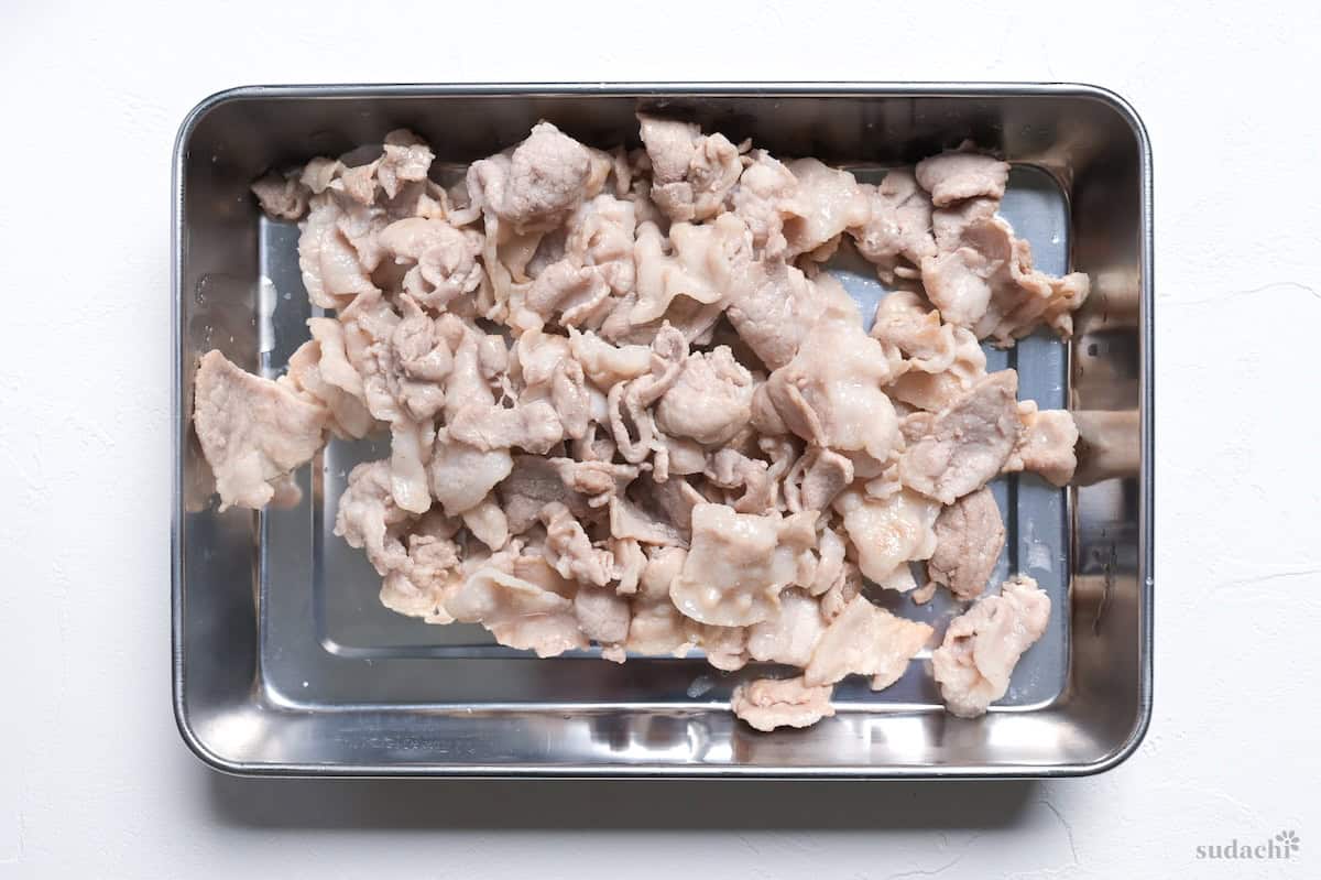 seared thinly sliced pork in a metal container