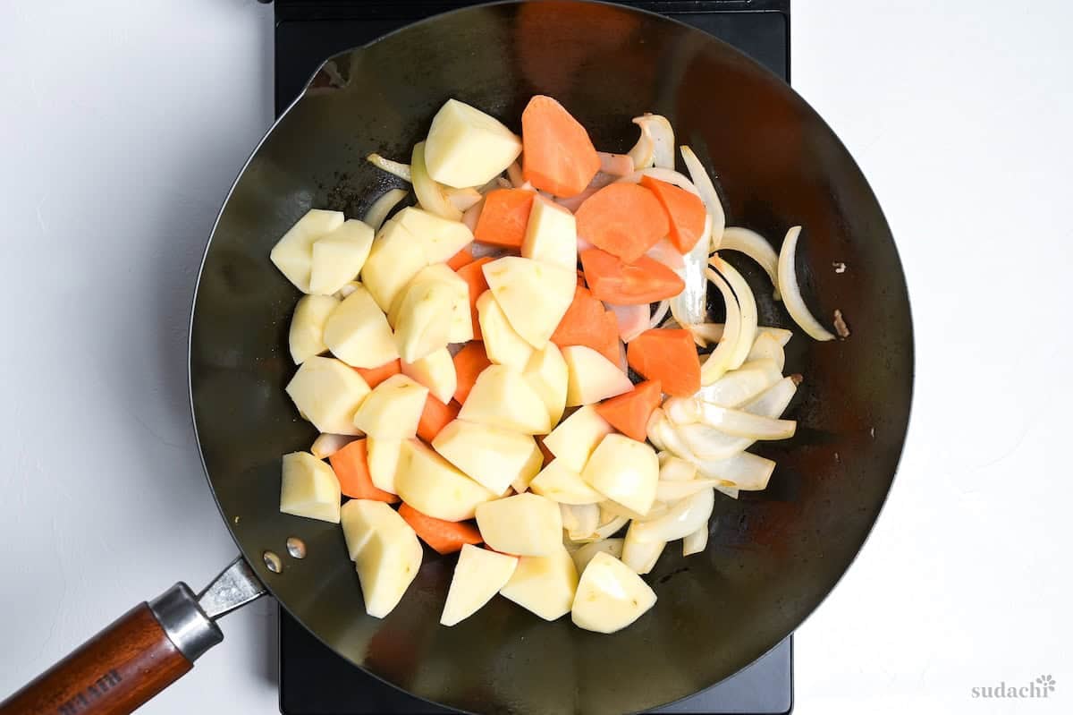 carrots and potatoes added to wok making nikujaga
