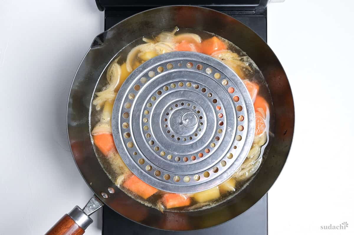 a drop lid placed over nikujaga while it simmers