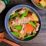 Nikujaga (Japanese meat and potato stew) with blanched snow peas in a blue bowl