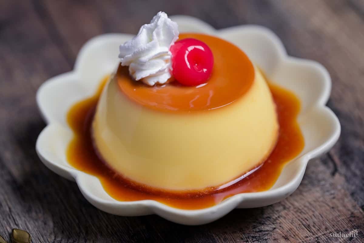 Japanese oven baked purin topped with whipped cream and a maraschino cherry on a flower shaped plate