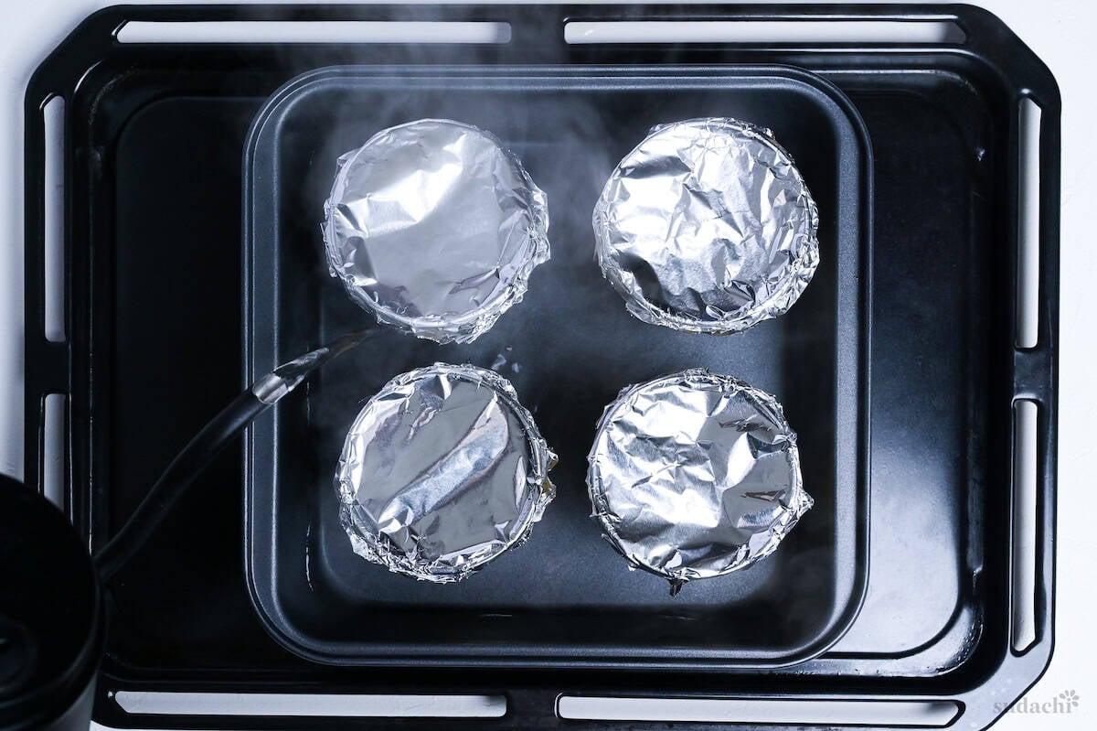 pouring hot water into baking pan with purin cups inside