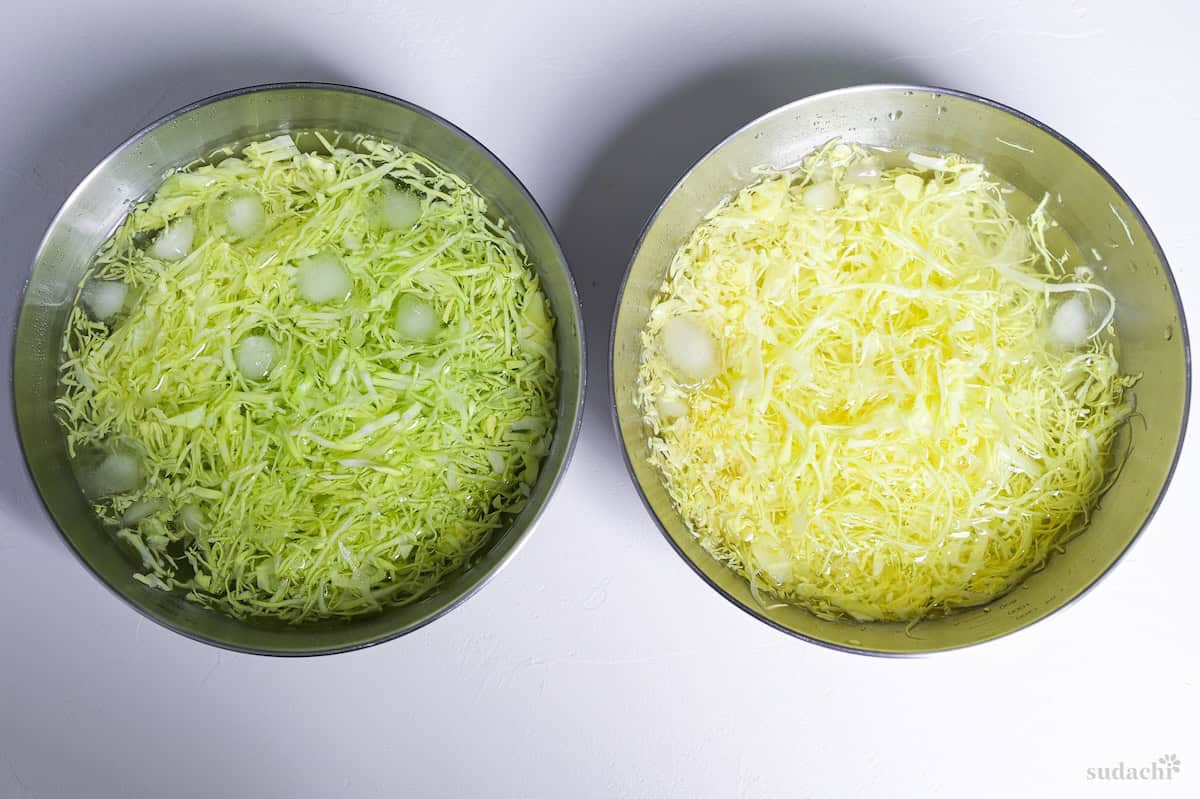 Two bowls of shredded green cabbage in a bowl of ice water. Left side is cut by knife, left side is cut with mandoline slicer