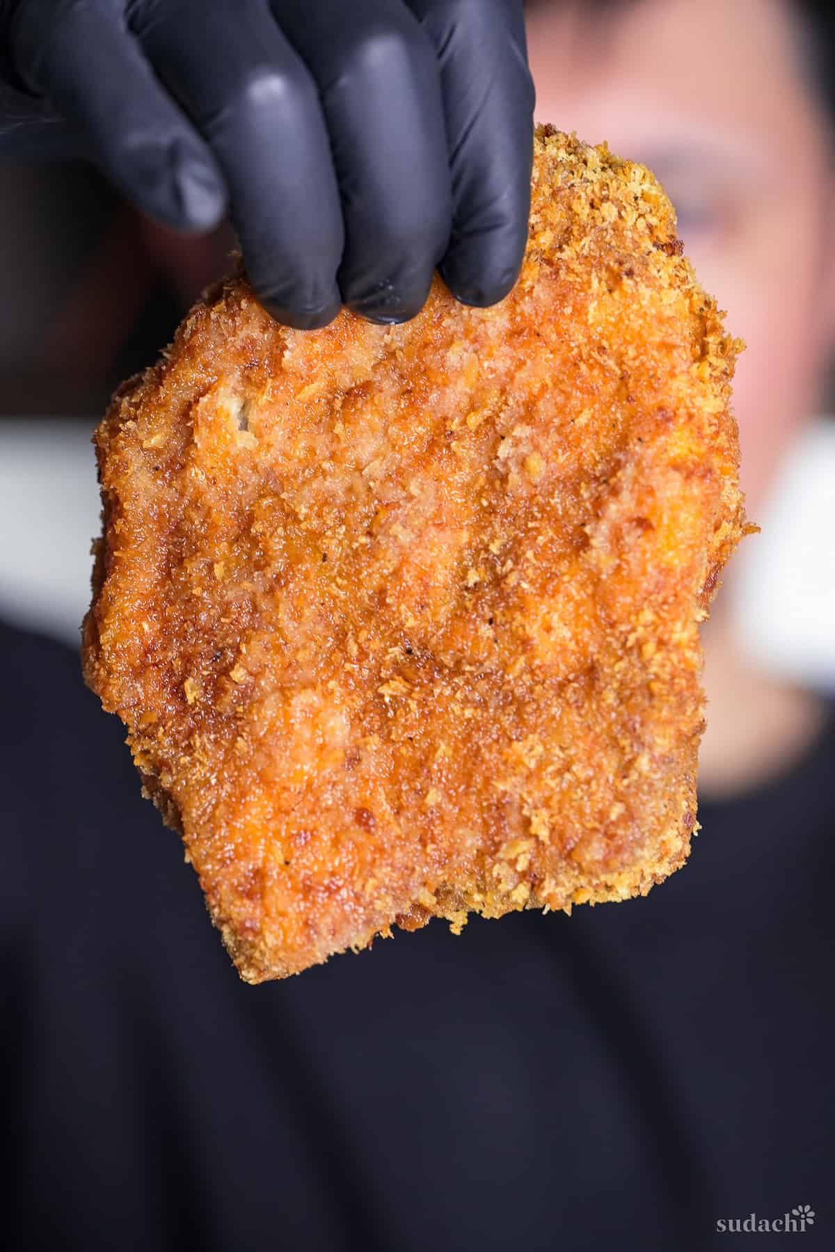 Yuto Omura holding up a freshly cooked tonkatsu (Japanese pork cutlet)