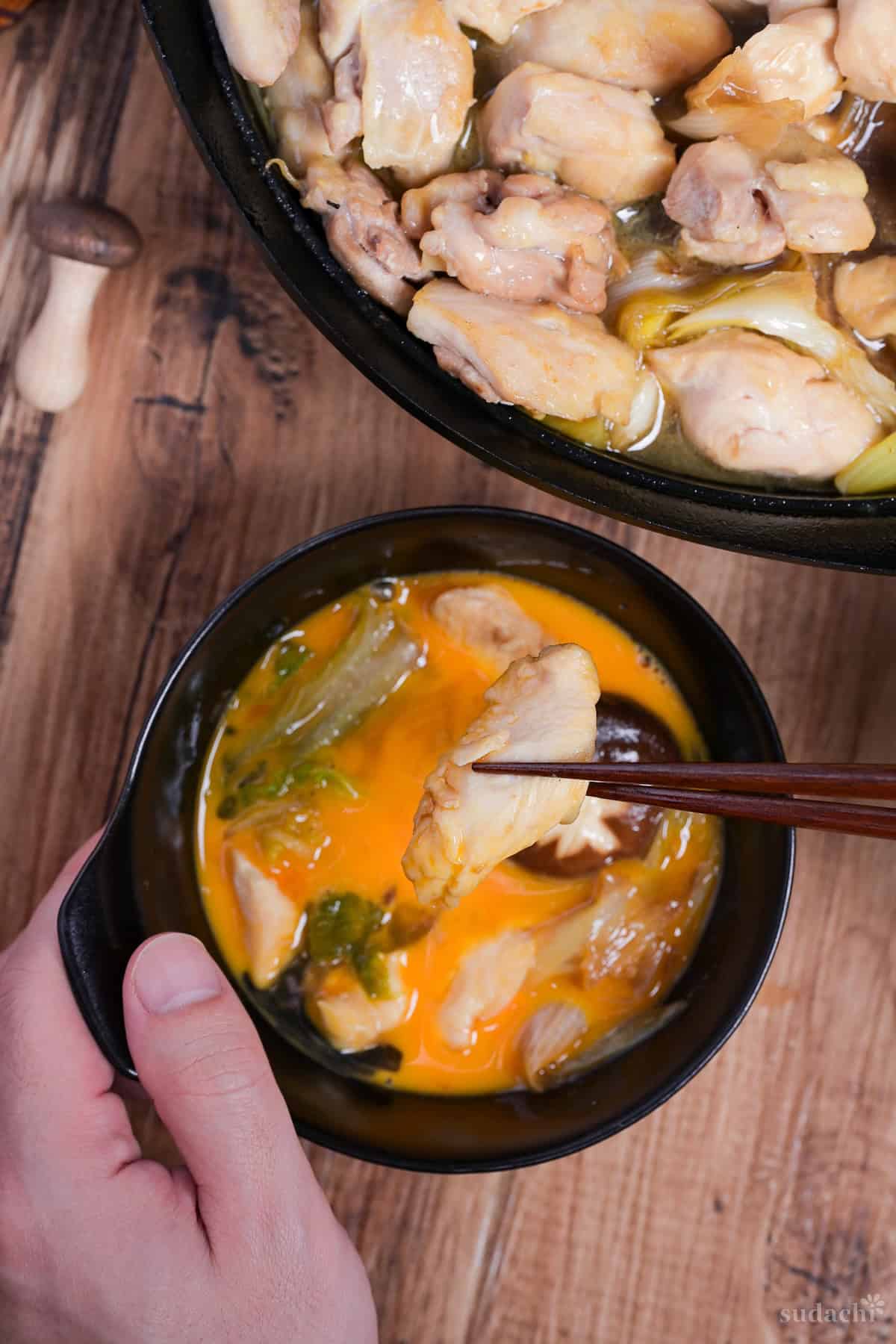 Dipping chicken sukiyaki in a bowl of whisked egg