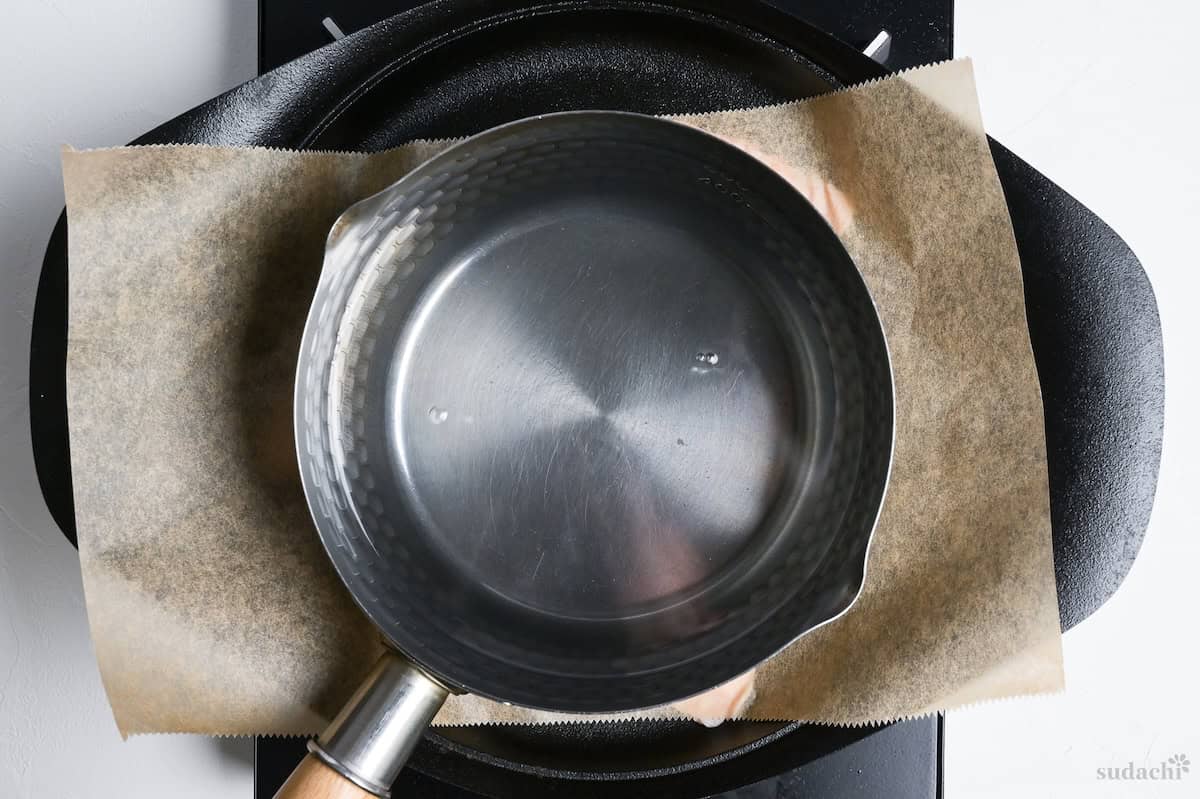 skin skin frying flat in a cast iron skillet, weighed down with a pot of water