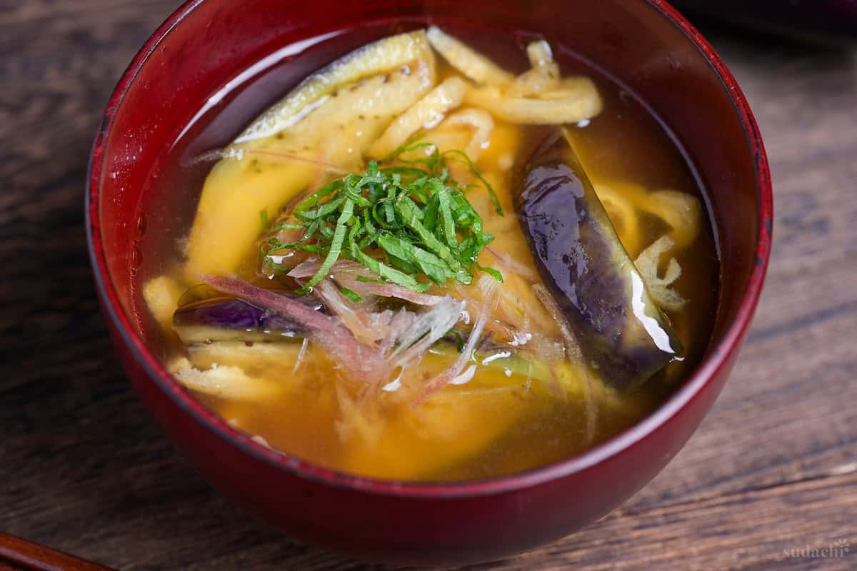 eggplant miso soup topped with Japanese ginger and shredded Perilla leaves in a red bowl close up