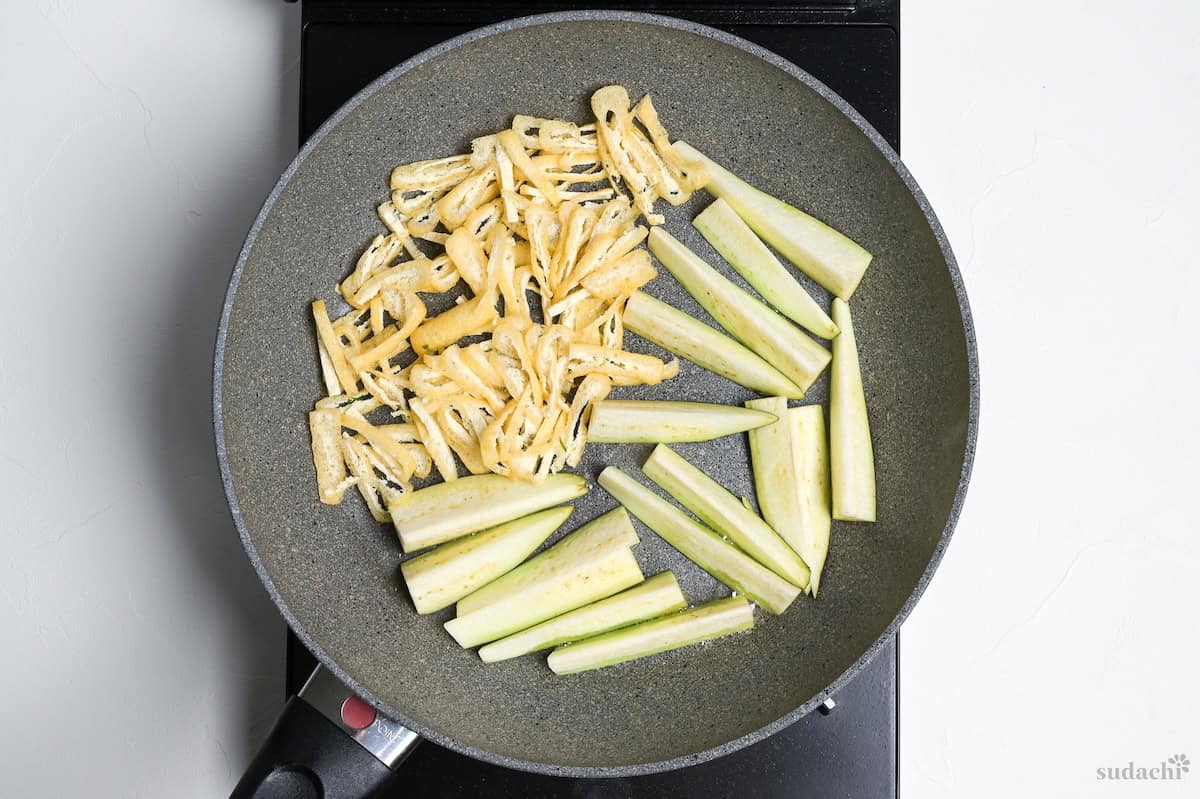 shredded tofu pouches and eggplant sticks in a frying pan on the stove top