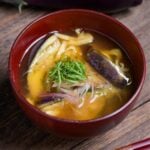 eggplant miso soup topped with Japanese ginger and shredded Perilla leaves in a red bowl