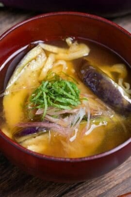 eggplant miso soup topped with Japanese ginger and shredded Perilla leaves in a red bowl