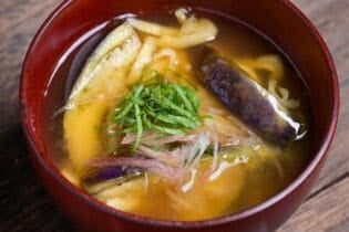 eggplant miso soup topped with Japanese ginger and shredded Perilla leaves in a red bowl