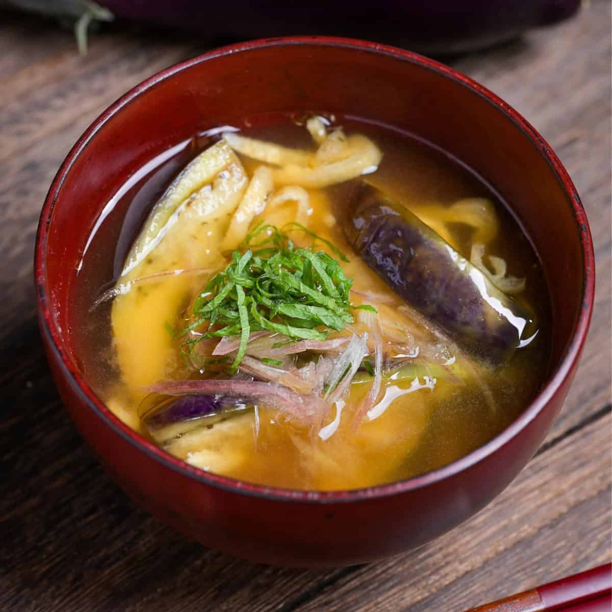 eggplant miso soup topped with Japanese ginger and shredded Perilla leaves in a red bowl