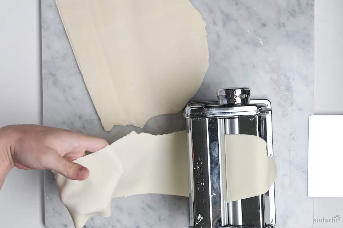 rolling gyoza dough through a pasta machine