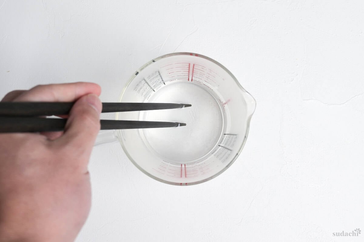 mixing hot water, sugar and salt in a glass measuring jug