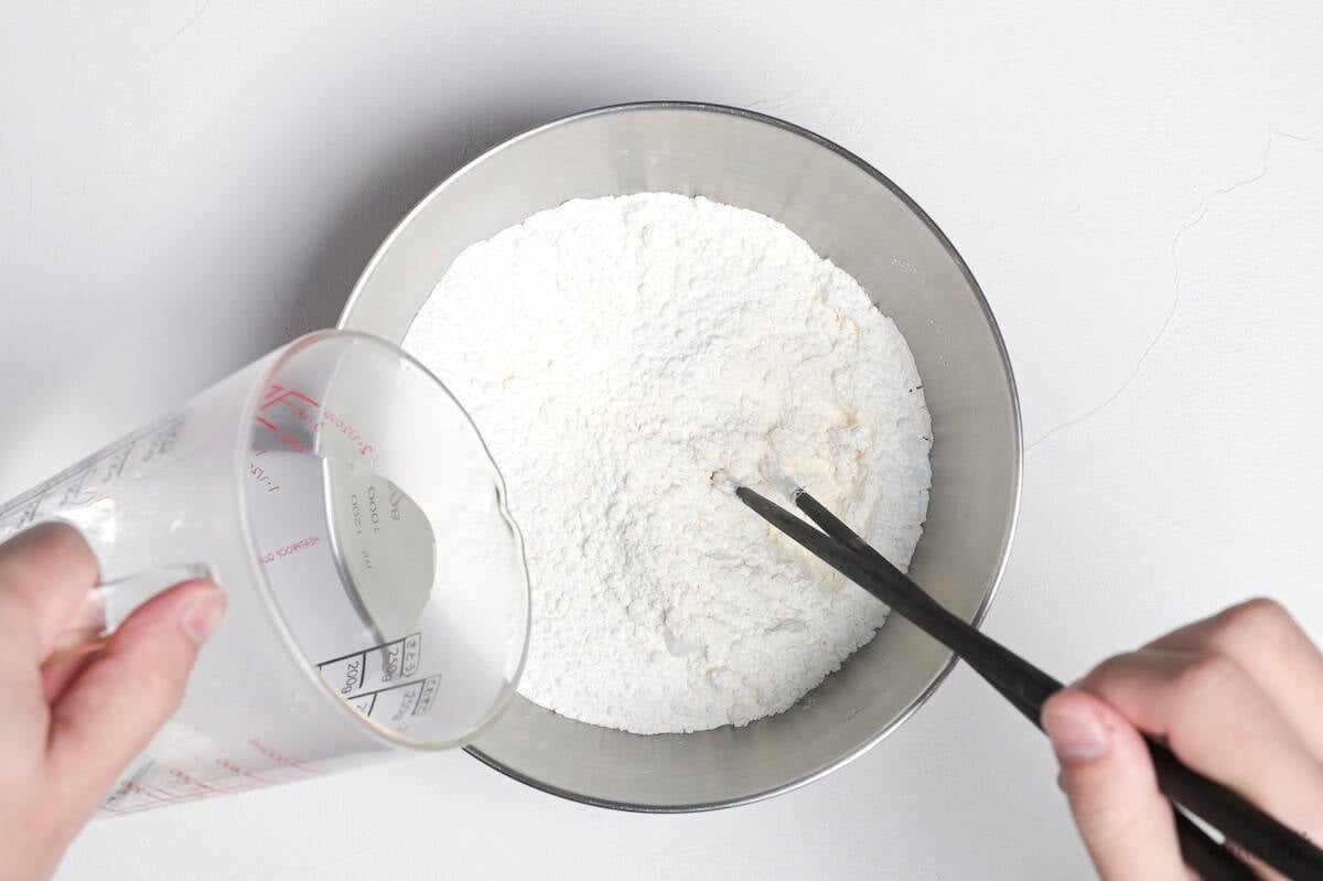 Pouring hot water into flour while whisking with chopsticks