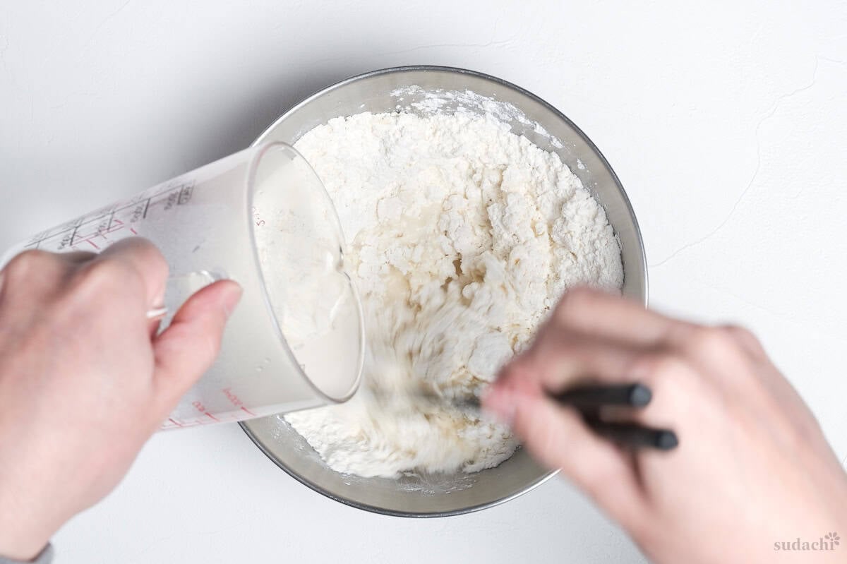 Gradually adding hot water to flour while mixing with chopsticks