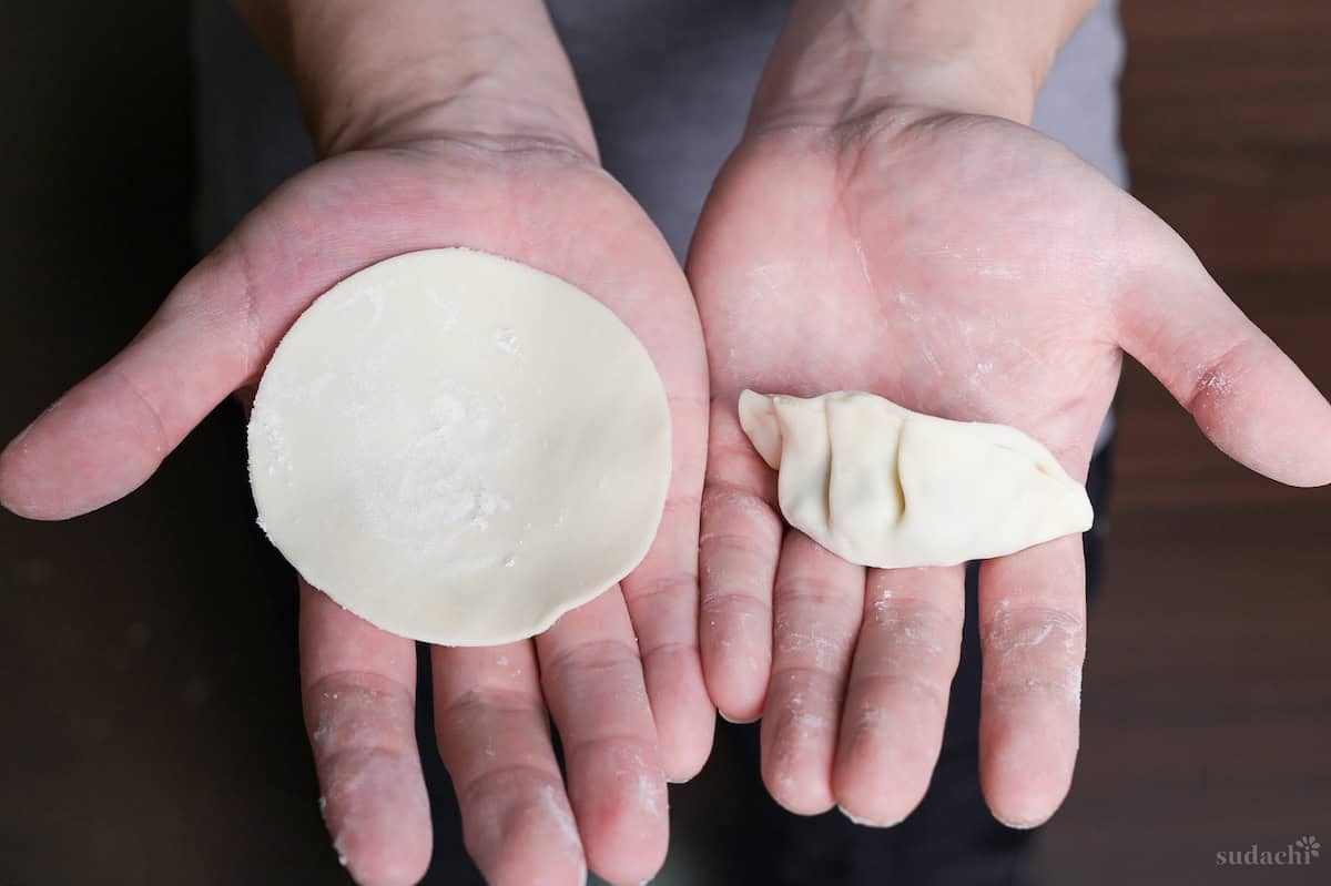 Yuto Omura holding a homemade gyoza skin in one hand, and an assembled gyoza with filling in the other hand.