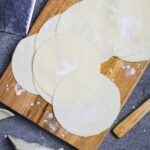 Homemade gyoza wrappers on a wooden cutting board