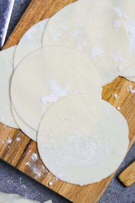 Homemade gyoza wrappers on a wooden cutting board