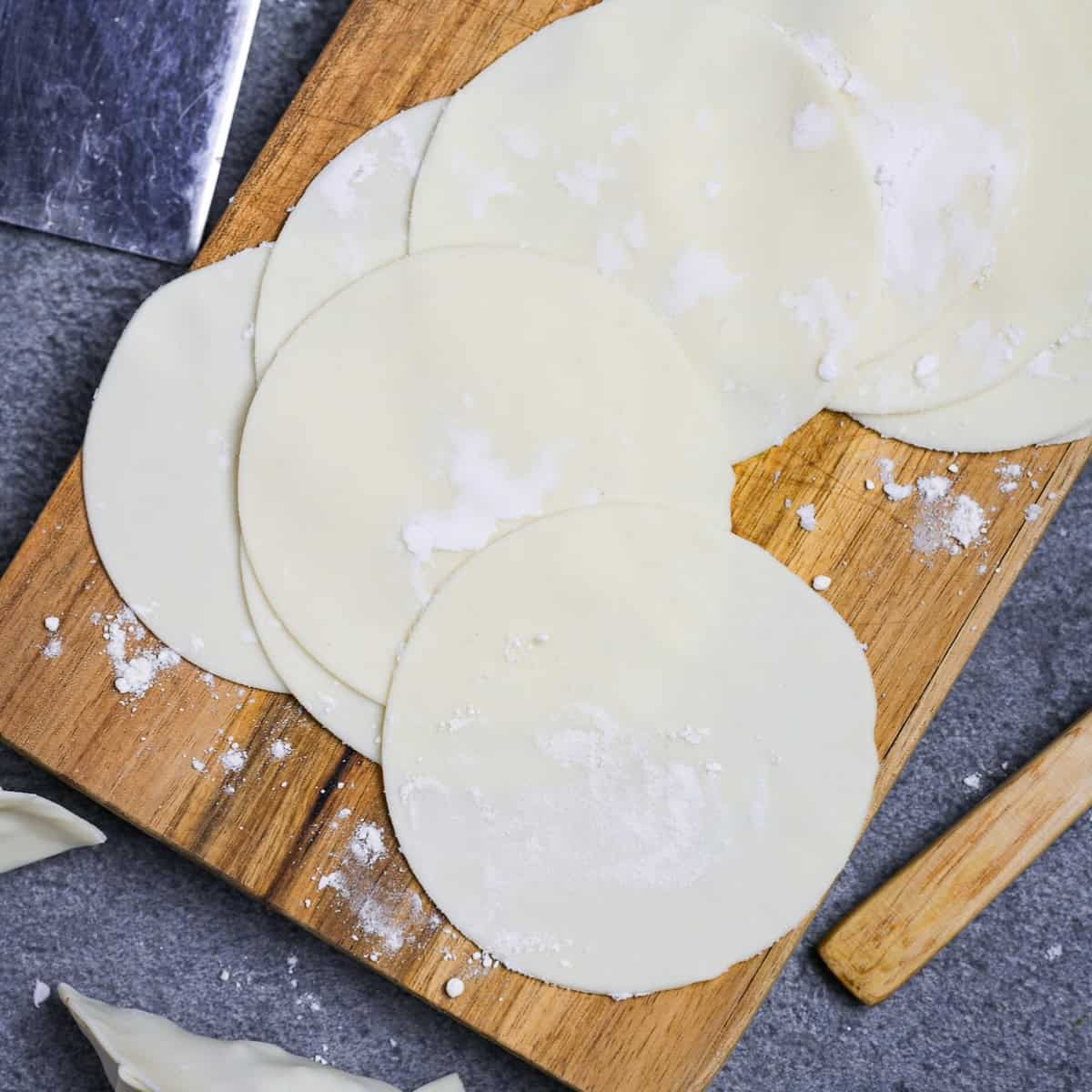 Homemade gyoza wrappers on a wooden cutting board