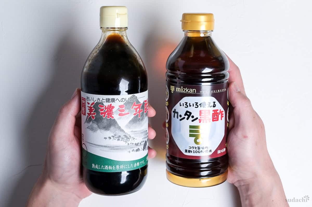 Yuto Omura holding up a bottle of red rice vinegar and black rice vinegar