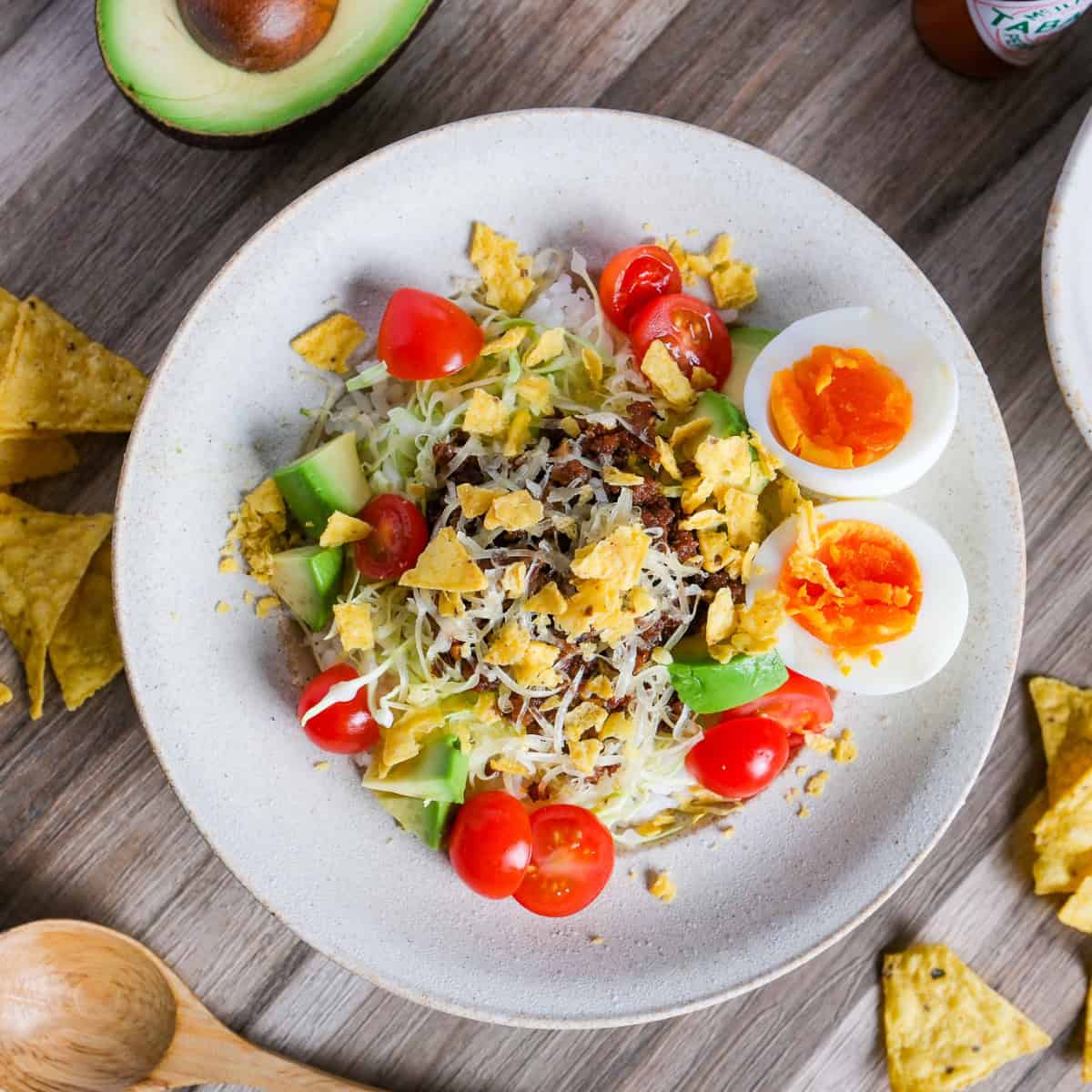 Okinawa Style Taco Rice topped with shredded cheese and crushed tortilla chips in an off-white dish