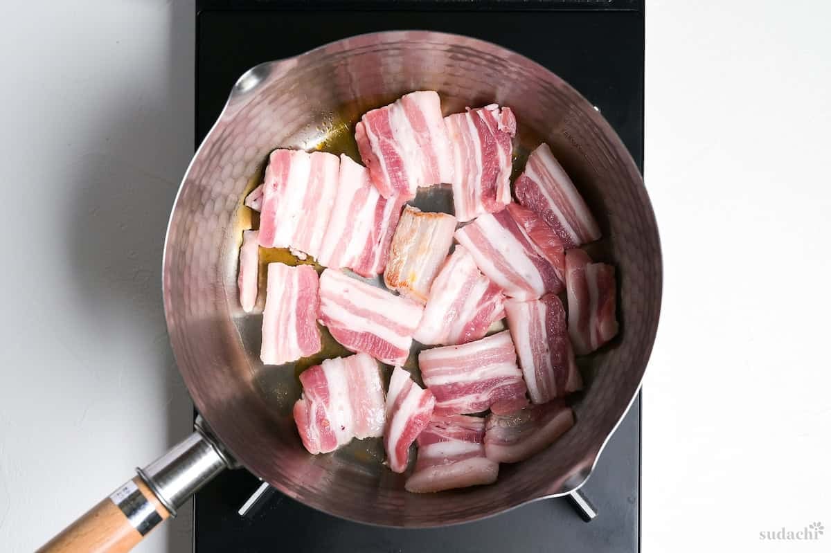 Searing pork belly slices in a pot to make tonjiru.