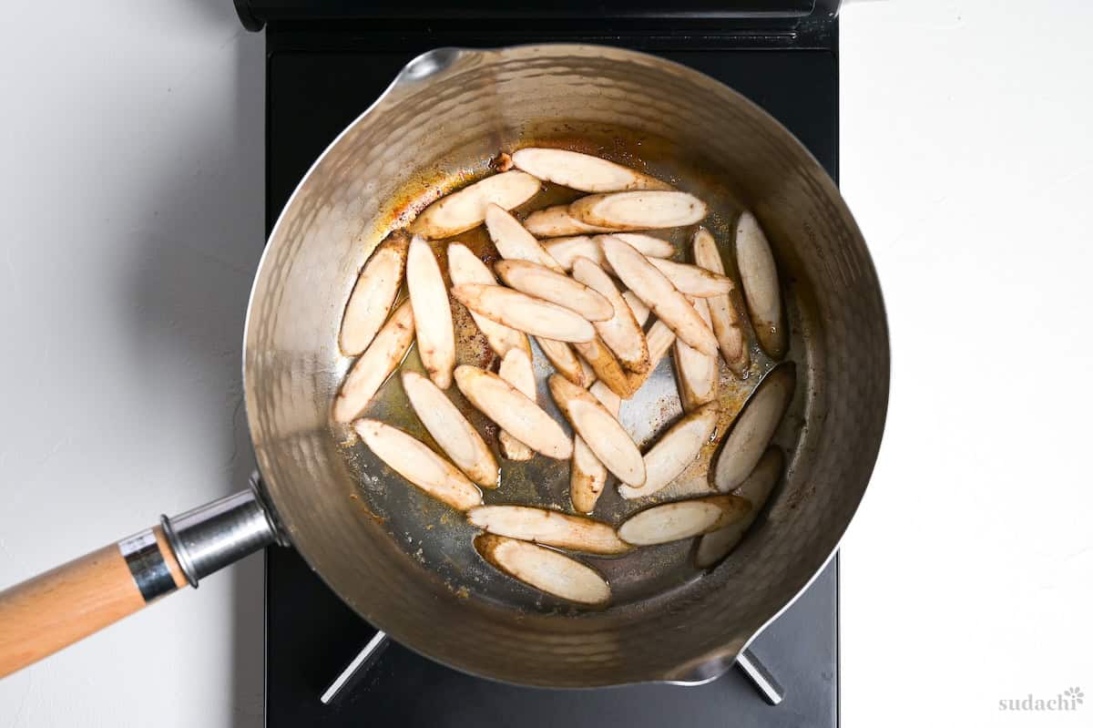 searing burdock root in a pot on the stove top.