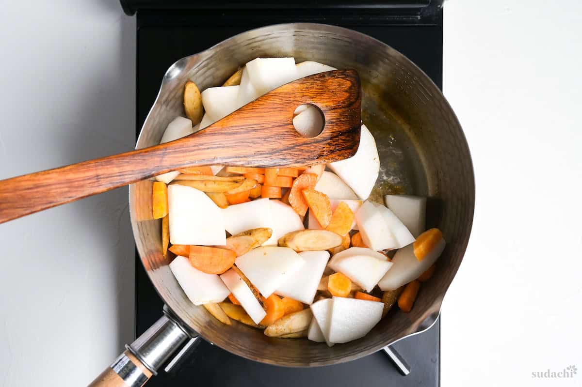 Searing vegetable ingredients for tonjiru in a pot on the stove top.