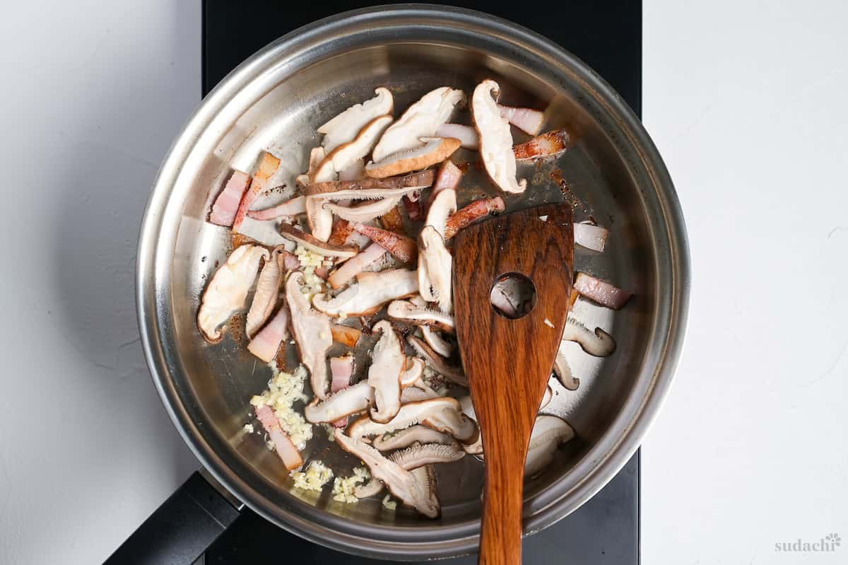 Seared bacon with mushrooms and garlic in a pan on the stove top
