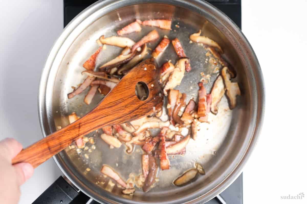 Searing bacon and onions in a frying pan on the stove top
