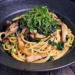 Japanese bacon and mushroom shoyu butter wafu pasta topped with shredded shiso leaves and nori served in a black pasta dish thumbnail