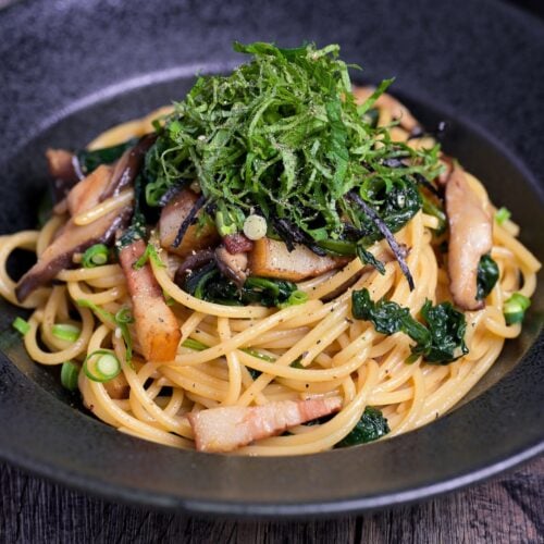 Japanese bacon and mushroom shoyu butter wafu pasta topped with shredded shiso leaves and nori served in a black pasta dish thumbnail